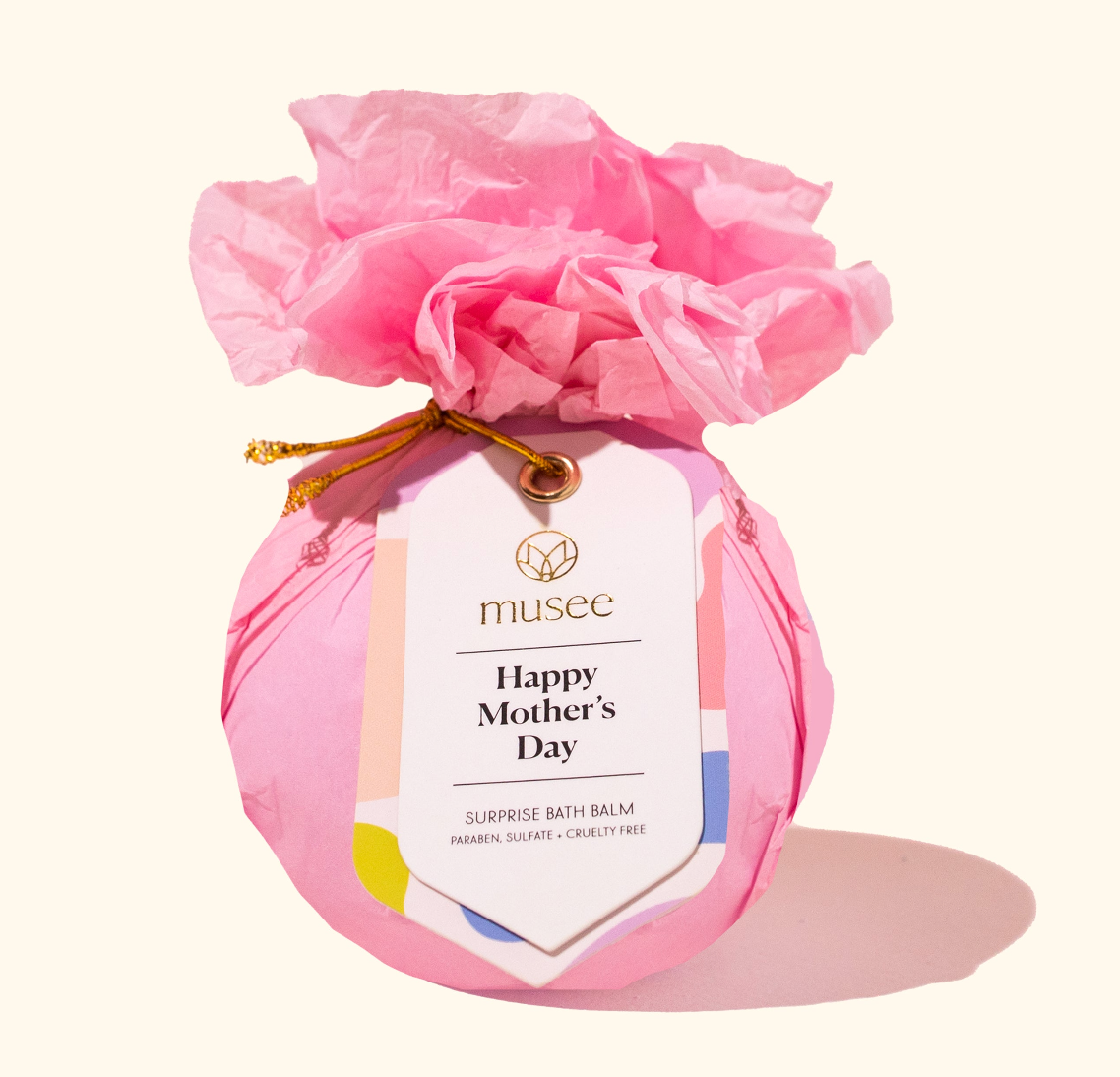 Pink bath bomb with a 'Happy Mother's Day' tag and decorative pink tissue paper on a white background.