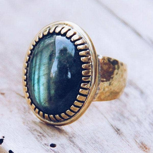 Silver ring with a blue green stone on a wooden surface