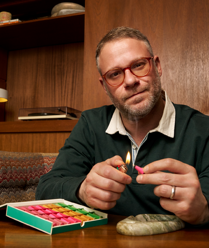 Man lighting a match with a box of matches on a wooden table