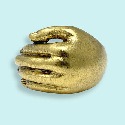 Gold hand-shaped object on a light blue background