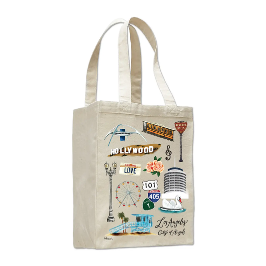 A natural canvas tote bag featuring a colorful graphic collage of Los Angeles landmarks and street signs, including the Hollywood sign, 101 freeway sign, and a microphone.