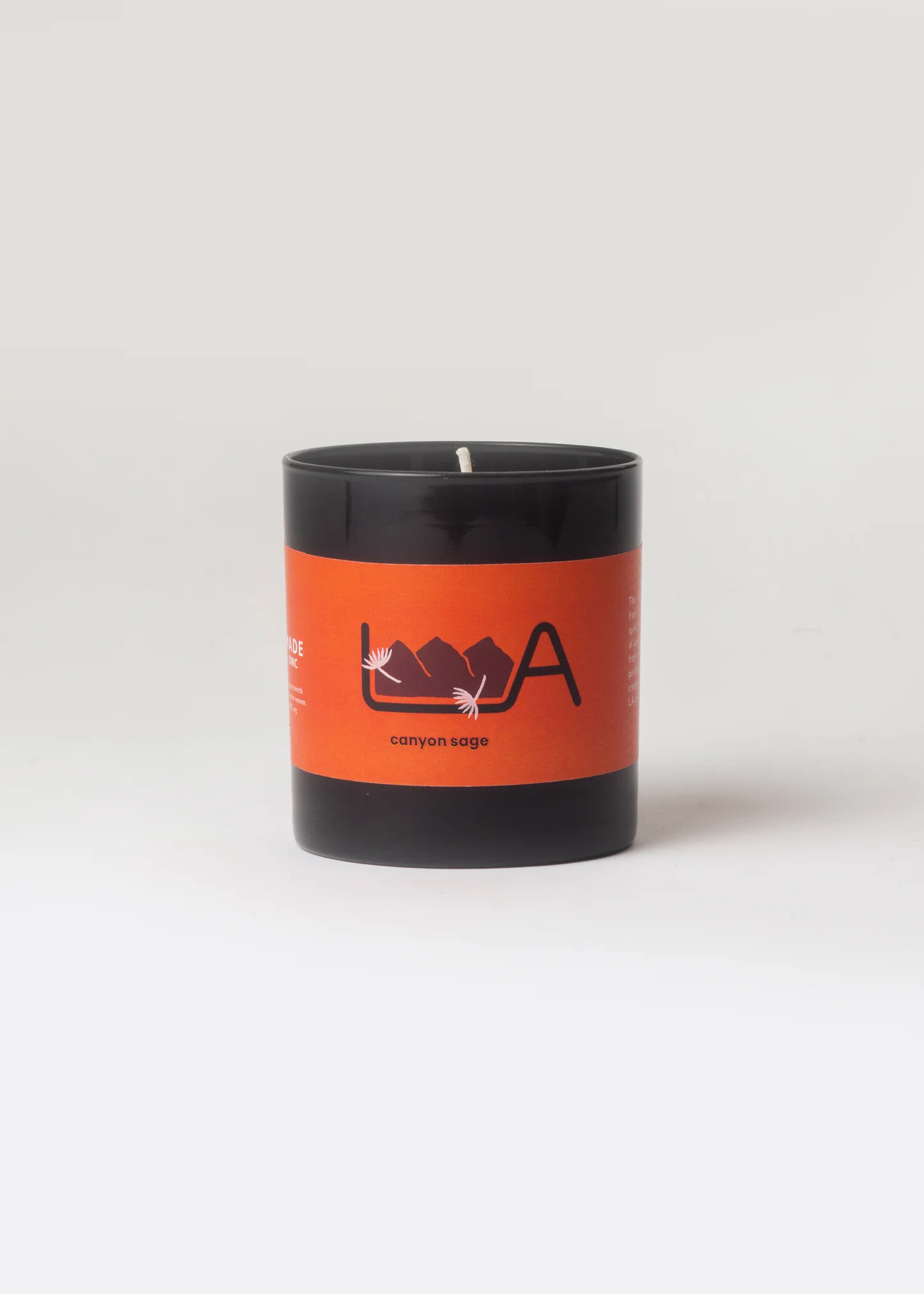 Candle with an orange label featuring a logo on a white background