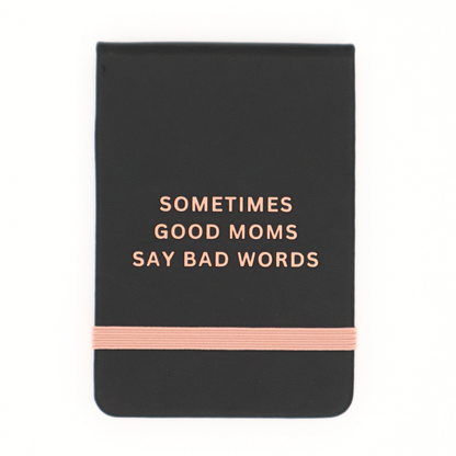 Black notebook with 'Sometimes Good Moms Say Bad Words' text and a pink band on a white background