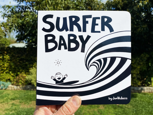 Book titled 'Surfer Baby' by Joe Vickers held in front of a natural background