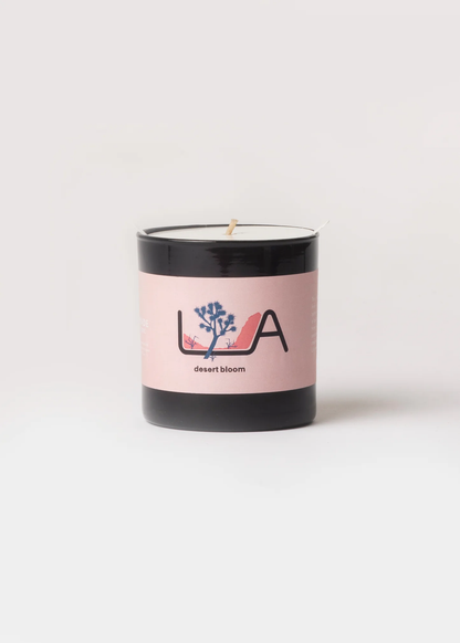 Candle with a pink label featuring a logo on a white background
