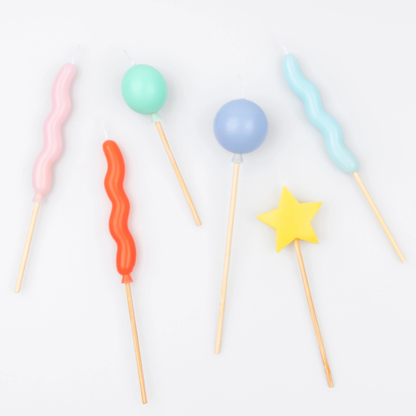 Colorful balloon shaped part candles with various shapes on a white background
