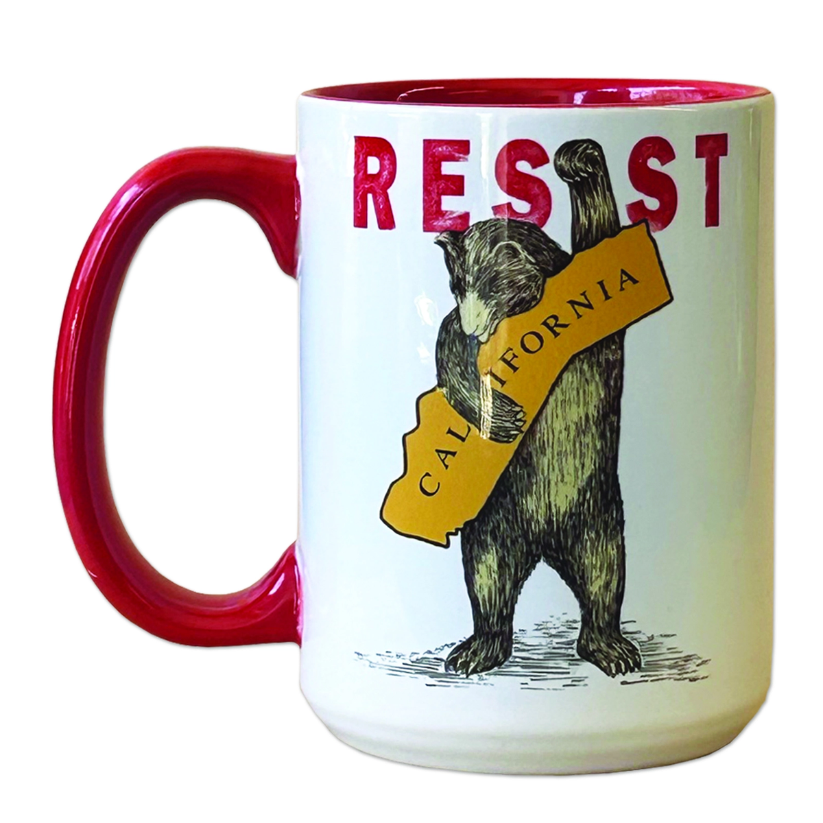 A white ceramic mug with a glossy red handle and red interior, featuring a printed graphic of a bear holding a yellow California-shaped banner with the word 'RESIST' above it.