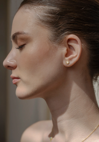 Side profile of a woman wearing small round earrings.