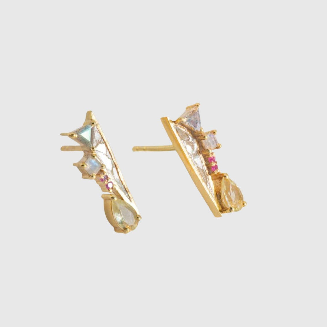 Gold earrings with gemstones on a light gray background