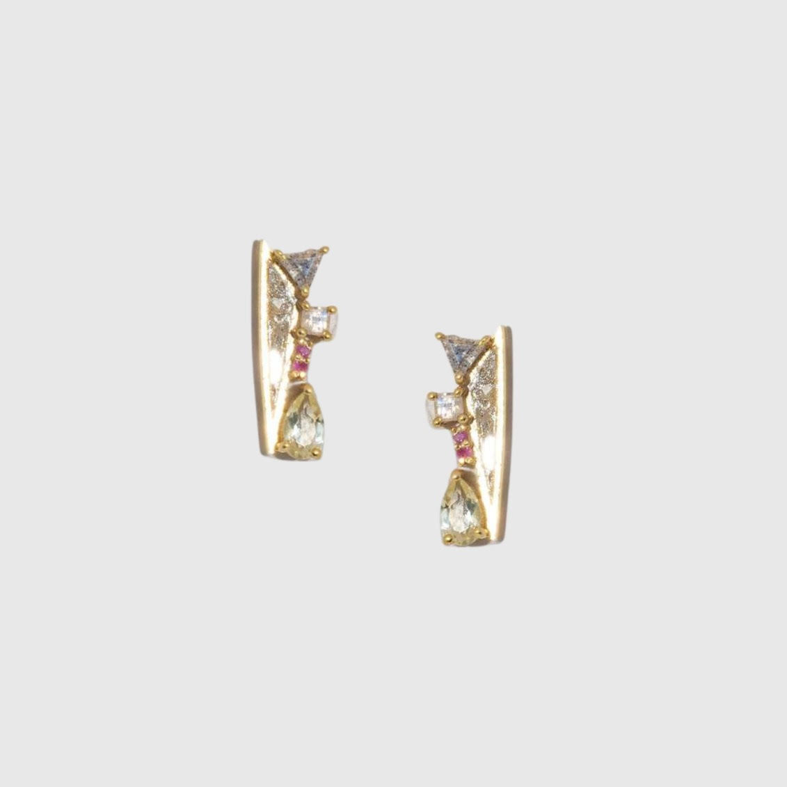 Gold earrings with gemstones on a light gray background